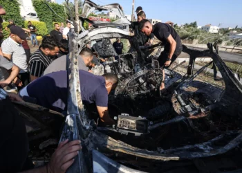 Varias personas revisan un automóvil atacado en un ataque aéreo de las Fuerzas de Defensa de Israel en la ciudad de Tulkarem, en Judea y Samaria, el 3 de agosto de 2024. (Jaafar Ashtiyeh/AFP)