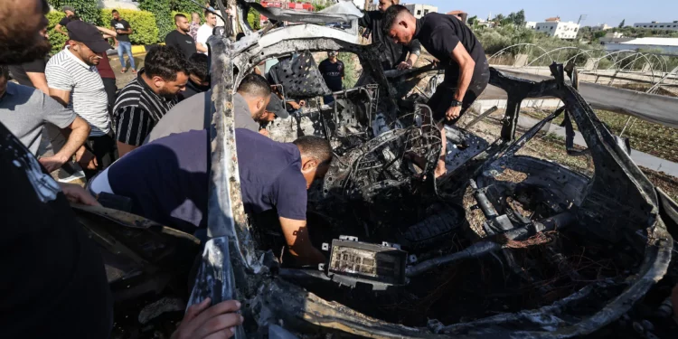 Varias personas revisan un automóvil atacado en un ataque aéreo de las Fuerzas de Defensa de Israel en la ciudad de Tulkarem, en Judea y Samaria, el 3 de agosto de 2024. (Jaafar Ashtiyeh/AFP)