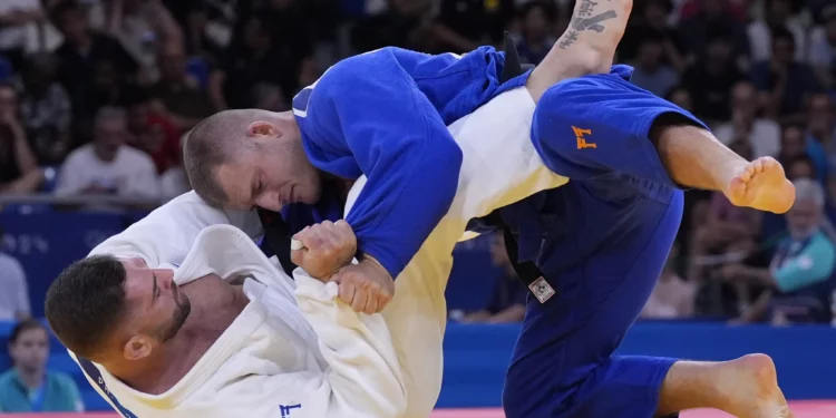 Peter Paltchik (blanco), de Israel, y Michael Korrel, de los Países Bajos, compiten durante su partido de repechaje de -100 kg en la competencia de judo durante los Juegos Olímpicos de Verano de 2024, el 1 de agosto de 2024, en París, Francia. (Foto AP/Eugene Hoshiko)