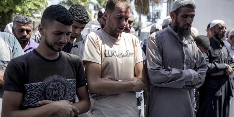 Mohammad Abu Al-Qumsan (centro) reza junto a los cadáveres de sus hijos gemelos de cuatro días de nacidos, asesinados en la Franja de Gaza, en un hospital de Deir al-Balah, el 13 de agosto de 2024. (Foto AP/Abdel Kareem Hana)