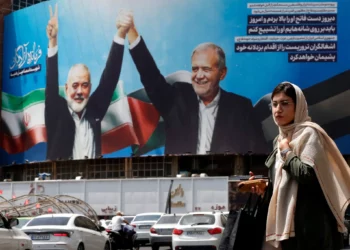 Una mujer pasa junto a un enorme cartel que representa al presidente iraní Masoud Pezeshkian (derecha) y al líder asesinado de Hamás, Ismail Haniyeh, en la plaza Valiasr de Teherán, el 8 de agosto de 2024. (AFP)