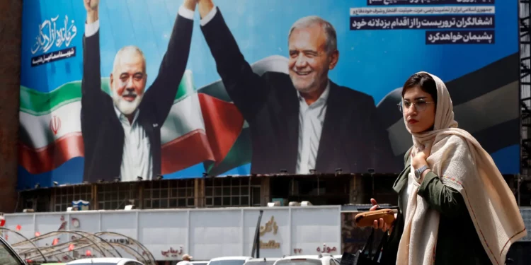 Una mujer pasa junto a un enorme cartel que representa al presidente iraní Masoud Pezeshkian (derecha) y al líder asesinado de Hamás, Ismail Haniyeh, en la plaza Valiasr de Teherán, el 8 de agosto de 2024. (AFP)