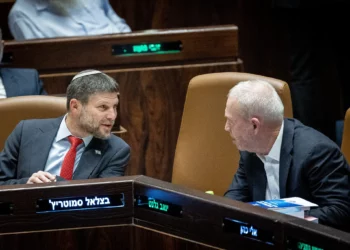 El ministro de Finanzas, Bezalel Smotrich, a la izquierda, habla con el ministro de Defensa, Yoav Gallant, durante un debate y votación sobre el presupuesto estatal en el pleno de la Knéset en Jerusalén, el 23 de mayo de 2023. (Yonatan Sindel/Flash90)