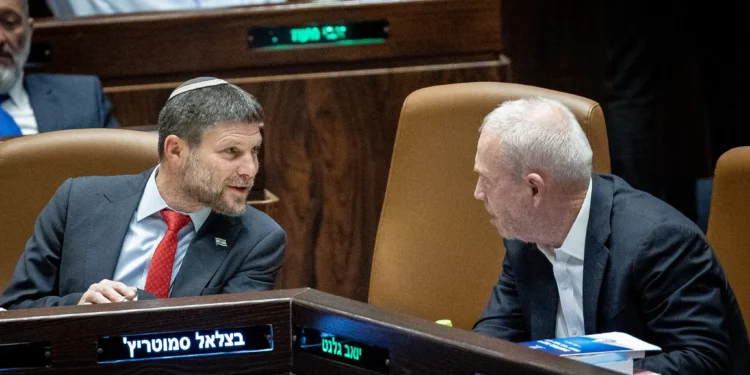 El ministro de Finanzas, Bezalel Smotrich, a la izquierda, habla con el ministro de Defensa, Yoav Gallant, durante un debate y votación sobre el presupuesto estatal en el pleno de la Knéset en Jerusalén, el 23 de mayo de 2023. (Yonatan Sindel/Flash90)