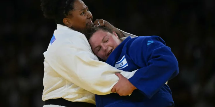 La brasileña Beatriz Souza y el israelí Raz Hershko (azul) se abrazan después de competir en la pelea por la medalla de oro de judo femenino +78 kg de los Juegos Olímpicos de París 2024 en el Champ-de-Mars Arena, en París el 2 de agosto de 2024. (Luis ROBAYO / AFP)