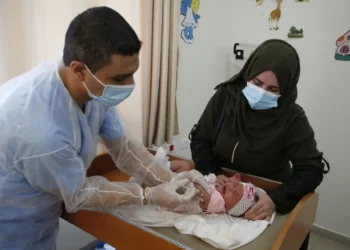 Un empleado de la UNRWA, que lleva una mascarilla debido a la pandemia del coronavirus COVID-19, administra la vacuna contra la polio y el rotavirus a niños en una clínica del campo de refugiados de Bureij, en el centro de la Franja de Gaza, el 9 de septiembre de 2020. (Mohammed ABED / AFP)