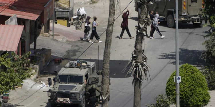 Soldados israelíes arrestan a un hombre palestino mientras otros pasan caminando con las manos en alto durante una operación militar en Jenin, Judea y Samaria, el 5 de septiembre de 2024. (Foto AP/Majdi Mohammed)