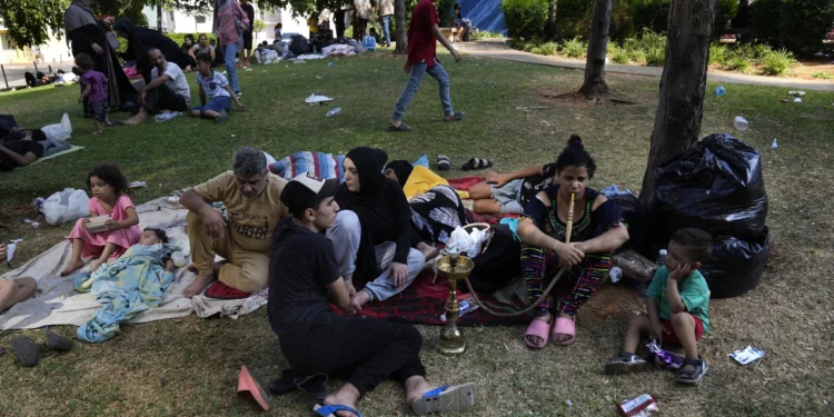 Personas que huyeron del suburbio sur de Beirut en medio de los continuos ataques aéreos israelíes contra objetivos de Hezbolá, sentadas en un parque en el centro de Beirut, Líbano, el 28 de septiembre de 2024. (Foto AP/Hussein Malla)