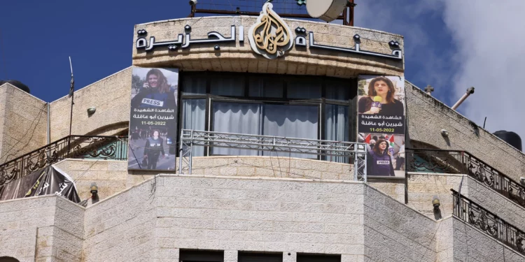 Imágenes de la periodista de Al Jazeera asesinada Shireen Abu Akleh cuelgan de la fachada del edificio que alberga la oficina de la estación de televisión en Ramallah, en Judea y Samaria, después de que Israel emitiera una orden de cierre de 45 días el 22 de septiembre de 2024. (Foto de JAAFAR ASHTIYEH / AFP)