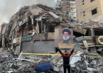 Un hombre muestra un retrato del asesinado jefe de Hezbolá, Hassan Nasrallah, frente a los escombros de un edificio en el lugar de un ataque aéreo israelí en los suburbios del sur de Beirut, el 12 de noviembre de 2024, en medio de la guerra en curso entre Israel y Hezbolá. (AFP)