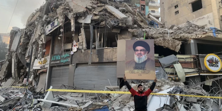 Un hombre muestra un retrato del asesinado jefe de Hezbolá, Hassan Nasrallah, frente a los escombros de un edificio en el lugar de un ataque aéreo israelí en los suburbios del sur de Beirut, el 12 de noviembre de 2024, en medio de la guerra en curso entre Israel y Hezbolá. (AFP)