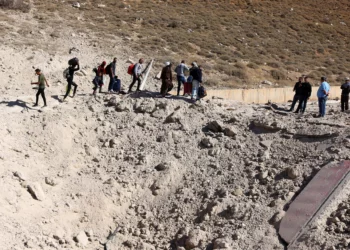 Personas que huyen de los intensos combates en Líbano caminan alrededor de un cráter causado por un ataque israelí contra la infraestructura de contrabando de armas de Hezbolá, en el área del cruce fronterizo de Masnaa, en Líbano, con Siria, el 4 de octubre de 2024. (Hassan Jarrah / AFP)