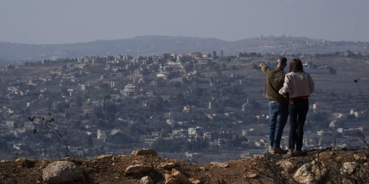 Una pareja israelí observa los edificios dañados en una aldea en el sur del Líbano, cerca de la frontera entre Israel y el Líbano, durante el alto el fuego entre Israel y Hezbolá, en el norte de Israel, el sábado 30 de noviembre de 2024. (Foto AP/Leo Correa)