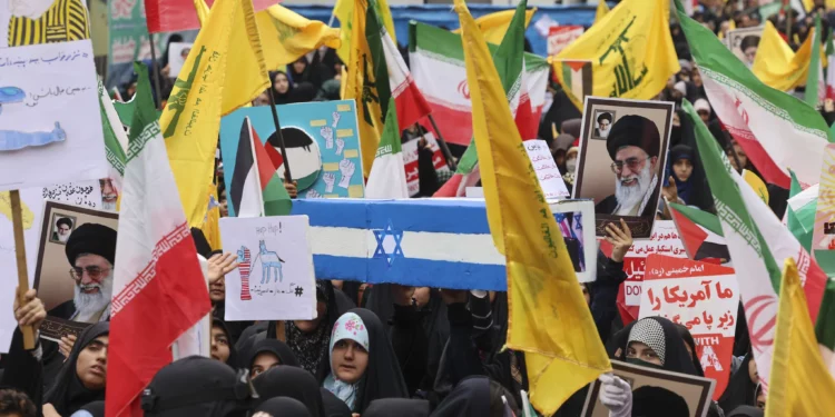 Las mujeres ondean banderas de Irán, Palestina y Hezbolá mientras llevan un ataúd simulado con la bandera israelí durante una manifestación frente a la antigua embajada de Estados Unidos en Teherán el 3 de noviembre de 2024 (ATTA KENARE / AFP)