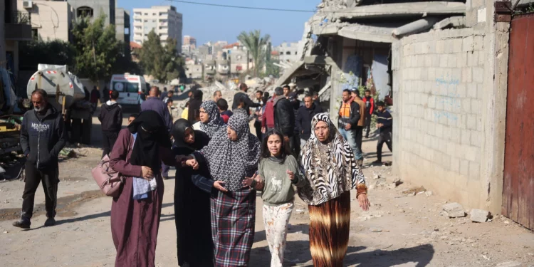 Palestinos pasan frente a una casa dañada en el campo de refugiados de Bureij, en el centro de la Franja de Gaza, el 2 de diciembre de 2024, en medio de la guerra en curso entre Israel y Hamás. (Foto de Eyad BABA / AFP)