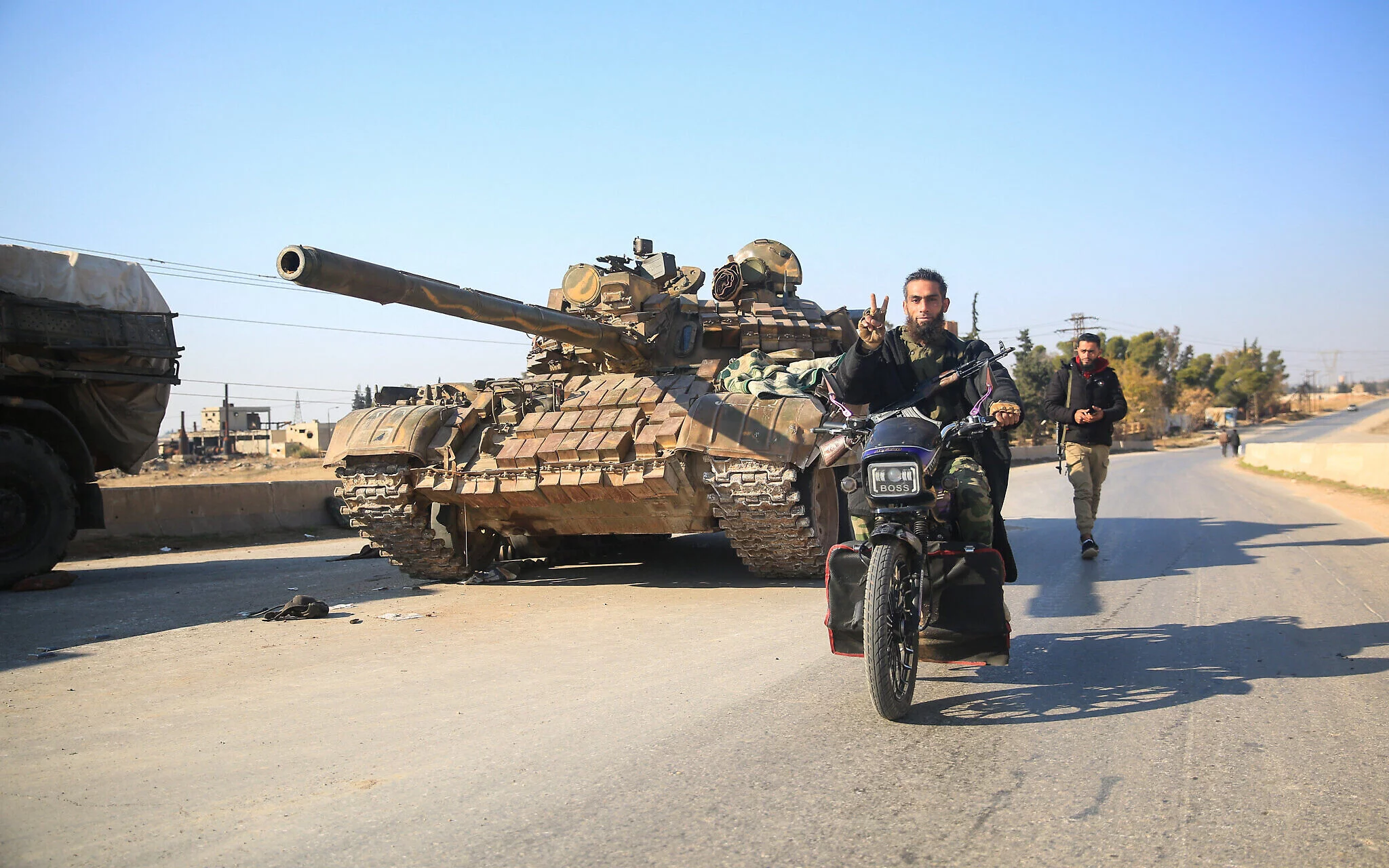 Los combatientes antigubernamentales pasan junto a equipos y vehículos militares del ejército sirio abandonados, mientras llegan a la ciudad de al-Safirah, al sureste de la ciudad de Alepo, Siria, el 3 de diciembre de 2024. (Aref Tammawi/AFP)