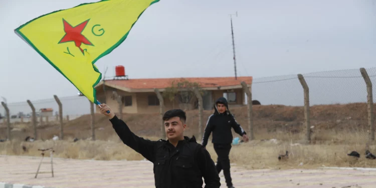 Un kurdo sirio ondea la bandera de las YPG (Unidades de Protección Popular) cerca del aeropuerto de Qamishli, en el noreste de Siria, el 8 de diciembre de 2024. (Delil SOULEIMAN / AFP)