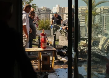 Un miembro de las fuerzas de seguridad israelíes toma fotografías en el lugar donde un dron explotó en el último piso de un edificio residencial en la ciudad de Yavne, en el sur de Israel, el 9 de diciembre de 2024. (Ahmad GHARABLI / AFP)