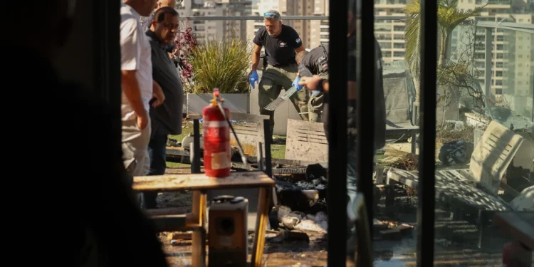 Un miembro de las fuerzas de seguridad israelíes toma fotografías en el lugar donde un dron explotó en el último piso de un edificio residencial en la ciudad de Yavne, en el sur de Israel, el 9 de diciembre de 2024. (Ahmad GHARABLI / AFP)