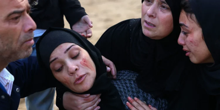 Una mujer palestina con el rostro manchado de sangre es consolada por otros mientras está de luto afuera del Hospital Nasser en Khan Younis, en el sur de la Franja de Gaza, el 12 de diciembre de 2024 (Bashar TALEB / AFP)