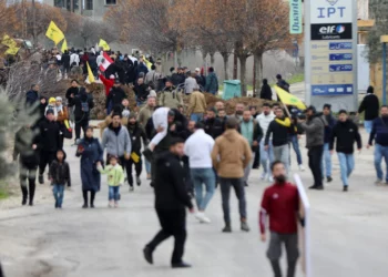 Libaneses con banderas de Hezbolá se reúnen cerca de las tropas israelíes en Burj al-Muluk, cerca de la aldea de Kfar Kila, en el sur del Líbano, donde las fuerzas israelíes permanecieron en el terreno después de que venciera la fecha límite para su retirada mientras los residentes intentaban regresar a sus hogares en la zona fronteriza, Líbano 26 de enero de 2025 (Reuters/Karamallah Daher)