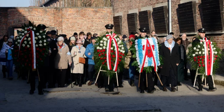 Los sobrevivientes, familiares y representantes del Memorial y Museo de Auschwitz-Birkenau colocan coronas de flores y encienden velas en el llamado Muro de la Muerte, junto al Bloque 11 del antiguo campo principal de Auschwitz I en Oswiecim, Polonia, el 27 de enero de 2025, durante las conmemoraciones del 80 aniversario de la liberación del campo de concentración y exterminio nazi alemán de Auschwitz-Birkenau por el Ejército Rojo. (Wojtek RADWANSKI / AFP)