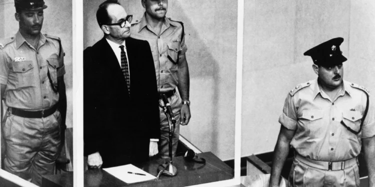 Adolf Eichmann de pie en su celda de cristal, flanqueado por guardias, en el tribunal de Jerusalén durante su juicio en 1961 por crímenes de guerra cometidos durante la Segunda Guerra Mundial. (Foto AP/Archivo)