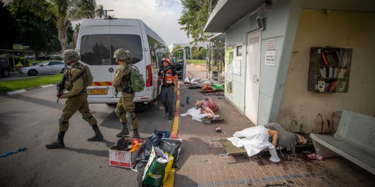 Soldados israelíes caminan junto a los cadáveres de personas asesinadas por terroristas de Hamás en la ciudad de Sderot, en el sur de Israel, el 7 de octubre de 2023. (Jamal Awad/Flash90)