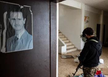 Un combatiente rebelde pasa junto a un retrato del derrocado presidente sirio Bashar al-Assad en el cuartel de la 4ª División del desmantelado ejército sirio, en la ciudad de Dummar, cerca de Damasco, el 23 de diciembre de 2024. (Sameer Al-DOUMY / AFP)