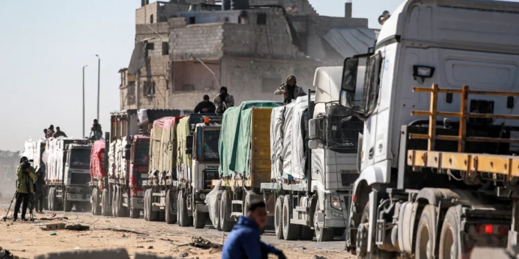 Un camarógrafo filma cómo los camiones que transportan ayuda humanitaria procedentes del cruce fronterizo de Kerem Shalom llegan a al-Shoka, al este de Rafah, en el sur de la Franja de Gaza, el 21 de enero de 2025. (Bashar TALEB / AFP)