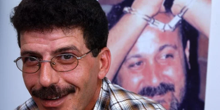 Una fotografía sin fecha de Qadura Fares, con una imagen del líder de Fatah Tanzim, Marwan Barghouti, encarcelado en el fondo. (Flash90)