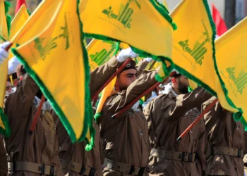 Miembros de Hezbolá levantan banderas del grupo terrorista libanés durante el funeral de un comandante y otro agente que murieron en un ataque con aviones no tripulados israelíes, en la aldea de Chehabiyeh, en el sur del Líbano, el 17 de abril de 2024. (Foto AP/Mohammed Zaatari)
