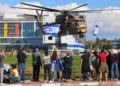 La gente ondea banderas israelíes mientras un helicóptero militar que transportaba a los cuatro soldados rehenes recién liberados aterriza en el Centro Médico Rabin en Petah Tikva el 25 de enero de 2025. (Yossi Zamir/AFP)