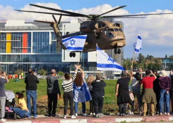 La gente ondea banderas israelíes mientras un helicóptero militar que transportaba a los cuatro soldados rehenes recién liberados aterriza en el Centro Médico Rabin en Petah Tikva el 25 de enero de 2025. (Yossi Zamir/AFP)