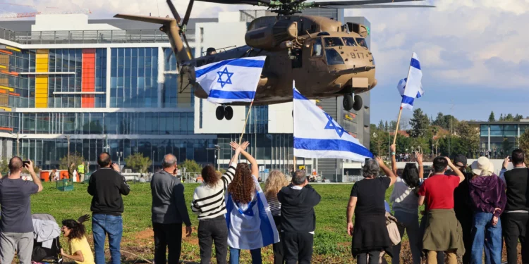 La gente ondea banderas israelíes mientras un helicóptero militar que transportaba a los cuatro soldados rehenes recién liberados aterriza en el Centro Médico Rabin en Petah Tikva el 25 de enero de 2025. (Yossi Zamir/AFP)