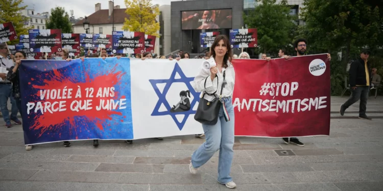 Manifestantes sostienen una pancarta que dice “violada a los 12 años por ser judía” durante una manifestación convocada por asociaciones como SOS Racismo y la Fundación Mujeres para denunciar el antisemitismo, en París el 20 de junio de 2024, tras la presunta violación en grupo por motivos antisemitas de una niña de 12 años en el suburbio parisino de Courbevoie. (Zakaria ABDELKAFI / AFP)