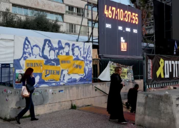 La gente pasa junto a una instalación que consiste en un reloj que cuenta el tiempo transcurrido desde la masacre de Hamás del 7 de octubre de 2023, instalada en una plaza frente al Museo de Arte de Tel Aviv, ahora llamada informalmente la “Plaza de los Rehenes”, en Tel Aviv el 16 de enero de 2025. (Jack Guez/AFP)