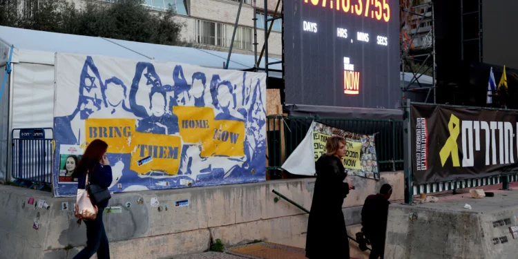 La gente pasa junto a una instalación que consiste en un reloj que cuenta el tiempo transcurrido desde la masacre de Hamás del 7 de octubre de 2023, instalada en una plaza frente al Museo de Arte de Tel Aviv, ahora llamada informalmente la “Plaza de los Rehenes”, en Tel Aviv el 16 de enero de 2025. (Jack Guez/AFP)