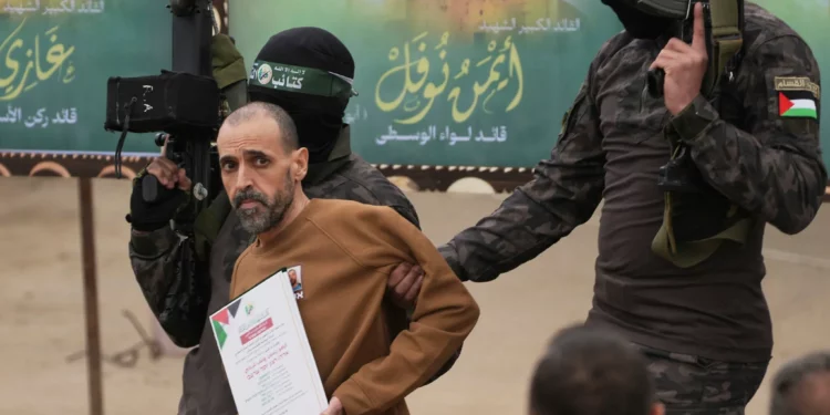 El rehén israelí Eli Sharabi, que se encuentra retenido como rehén por Hamas en Gaza desde el 7 de octubre de 2023, es paseado por hombres armados de Hamas antes de ser entregado a la Cruz Roja en Deir al-Balah, en el centro de la Franja de Gaza, el sábado 8 de febrero de 2025. (Foto AP/Abdel Kareem Hana)