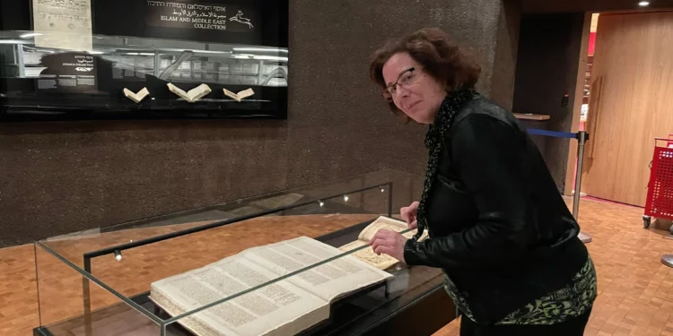 Rachel Neiman, portavoz de la Biblioteca Nacional de Israel, examina un manuscrito del siglo XV que contiene Mezukak Shivatayim ('Destilado siete veces'), un comentario previamente perdido sobre la Misheh Torá de Maimonines que se exhibe en la Biblioteca Nacional de Israel en febrero de 2025. (Rossella Tercatin/Times of Israel)