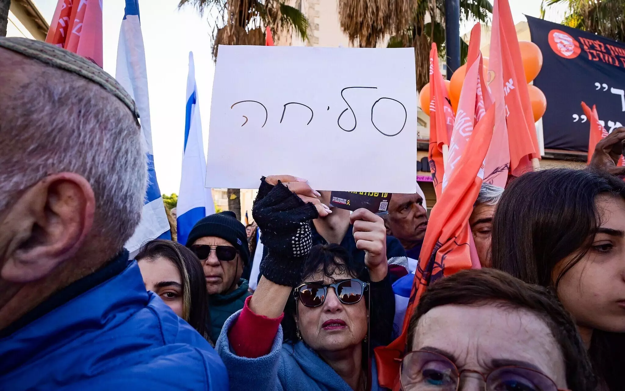 Una mujer sostiene un cartel que dice “lo siento” mientras la gente presenta sus respetos durante la procesión fúnebre de los rehenes asesinados Shiri Bibas y sus hijos Ariel y Kfir en Rishon LeZion, el 26 de febrero de 2025 (Avshalom Sassoni/Flash90)