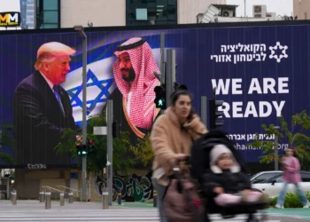 La gente pasa frente a un cartel electrónico que muestra al presidente de Estados Unidos, Donald Trump, a la izquierda, estrechando la mano del príncipe heredero saudí, Mohammed bin Salman, con un texto que dice: "Estamos listos", en Tel Aviv, el 3 de febrero de 2025. (Foto AP/ Ariel Schalit)