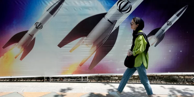 Una mujer pasa junto a una pancarta que muestra el lanzamiento de misiles en el norte de Teherán, Irán, el 19 de abril de 2024. (Foto AP/Vahid Salemi)