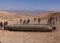 Israelíes observan los restos de un misil iraní, en el desierto de Negev, cerca de Arad, el 3 de octubre de 2024. (MENAHEM KAHANA / AFP)