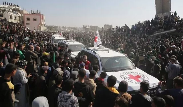 Una multitud rodea los vehículos de la Cruz Roja a su llegada al lugar de la entrega de rehenes tailandeses e israelíes en Jan Yunis, en el sur de la Franja de Gaza, el jueves 30 de enero de 2025. (AP/Jehad Alshrafi)