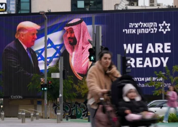 La gente pasa frente a un cartel electrónico que muestra al presidente de Estados Unidos, Donald Trump, a la izquierda, estrechando la mano del príncipe heredero saudí, Mohammed bin Salman, con el mensaje a favor de la normalización "Estamos listos", en Tel Aviv, el 3 de febrero de 2025. (Foto AP/ Ariel Schalit)