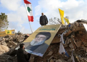 La gente coloca una imagen del líder asesinado de Hezbolá, Hassan Nasrallah, sobre los escombros del santuario de Shamoun al-Safa, en el pueblo de Shamaa, en Tiro, en el sur del Líbano, el 31 de enero de 2025. (Mahmoud ZAYYAT / AFP)