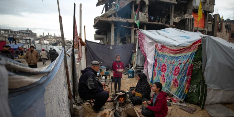 Una familia palestina cocina en el fuego junto a su tienda de campaña, en una zona destruida en gran parte durante la guerra contra Hamás en Jabaliya, Franja de Gaza, el 11 de febrero de 2025. (Jehad Alshrafi/AP)