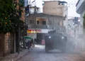 Palestinian shopkeepers look as Israeli armored vehicles drive by during a raid in the eastern neighborhood of Jenin amid a weeks-long operation in the West Bank on March 4, 2025. (Jaafar ASHTIYEH / AFP)