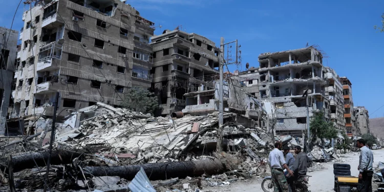 Personas frente a edificios dañados en la ciudad de Duma, lugar donde se presunto ataque con armas químicas, cerca de Damasco, Siria, el 16 de abril de 2018. (Hassan Ammar/AP)